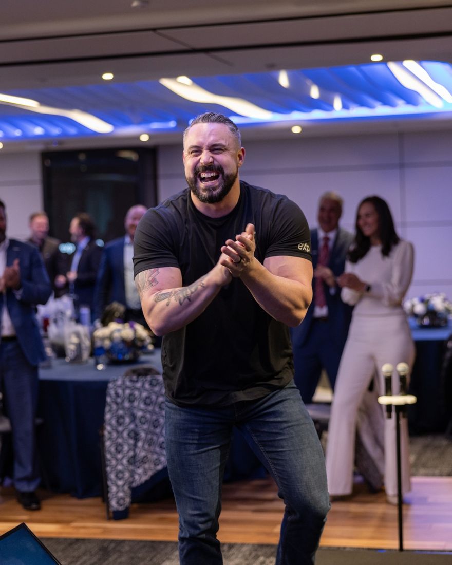 Blake Suddath clapping on stage in front of a room of agents in New York