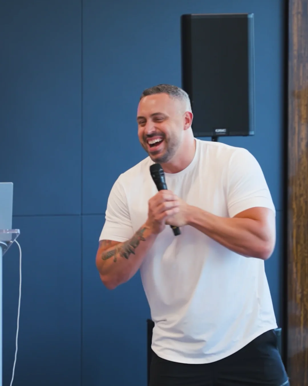 Blake Suddath laughing on stage with a microphone
